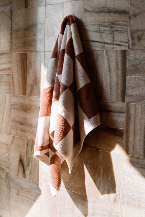 Pantone names mocha mousse as there colour of the year 2025, here you see a checked towel from HAY hanging on a wall in the same brown tone. 