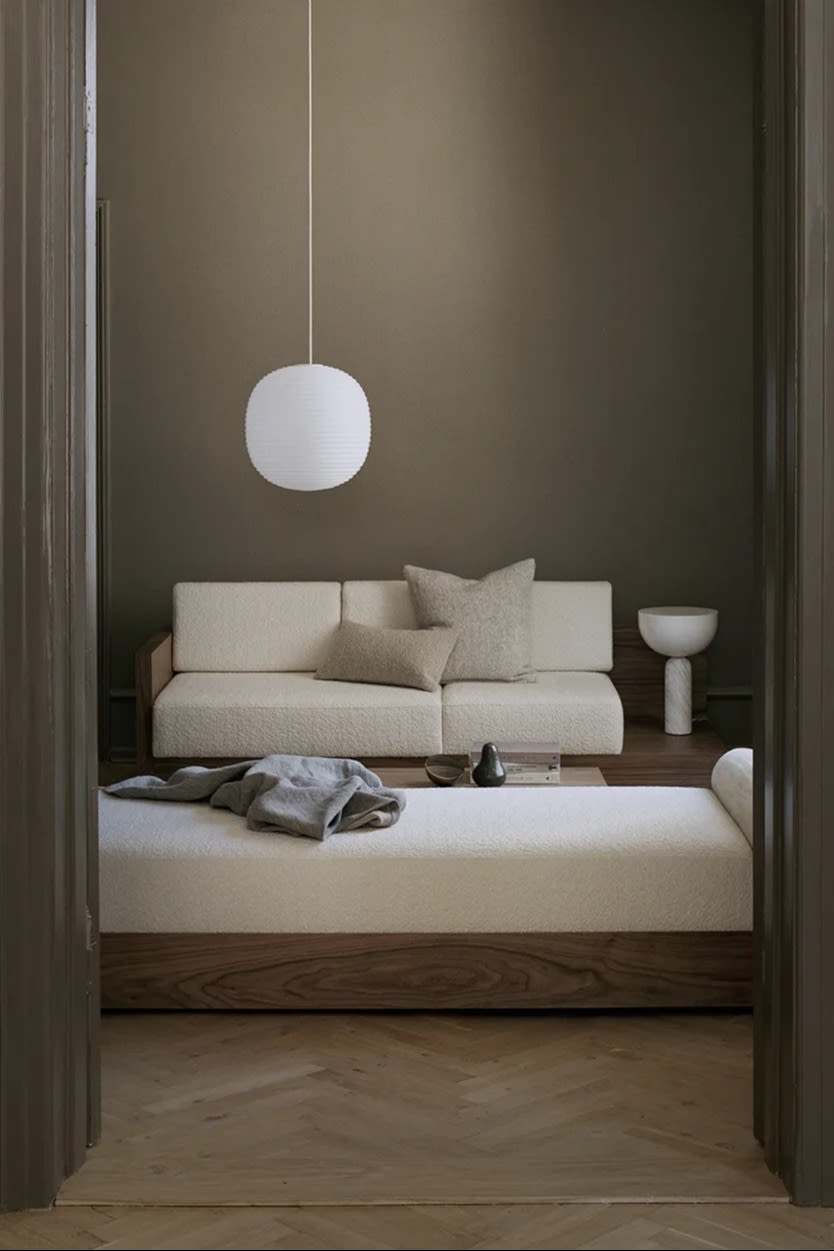 The Lantern ceiling light from New Works hanging in a living room with cream coloured sofas.