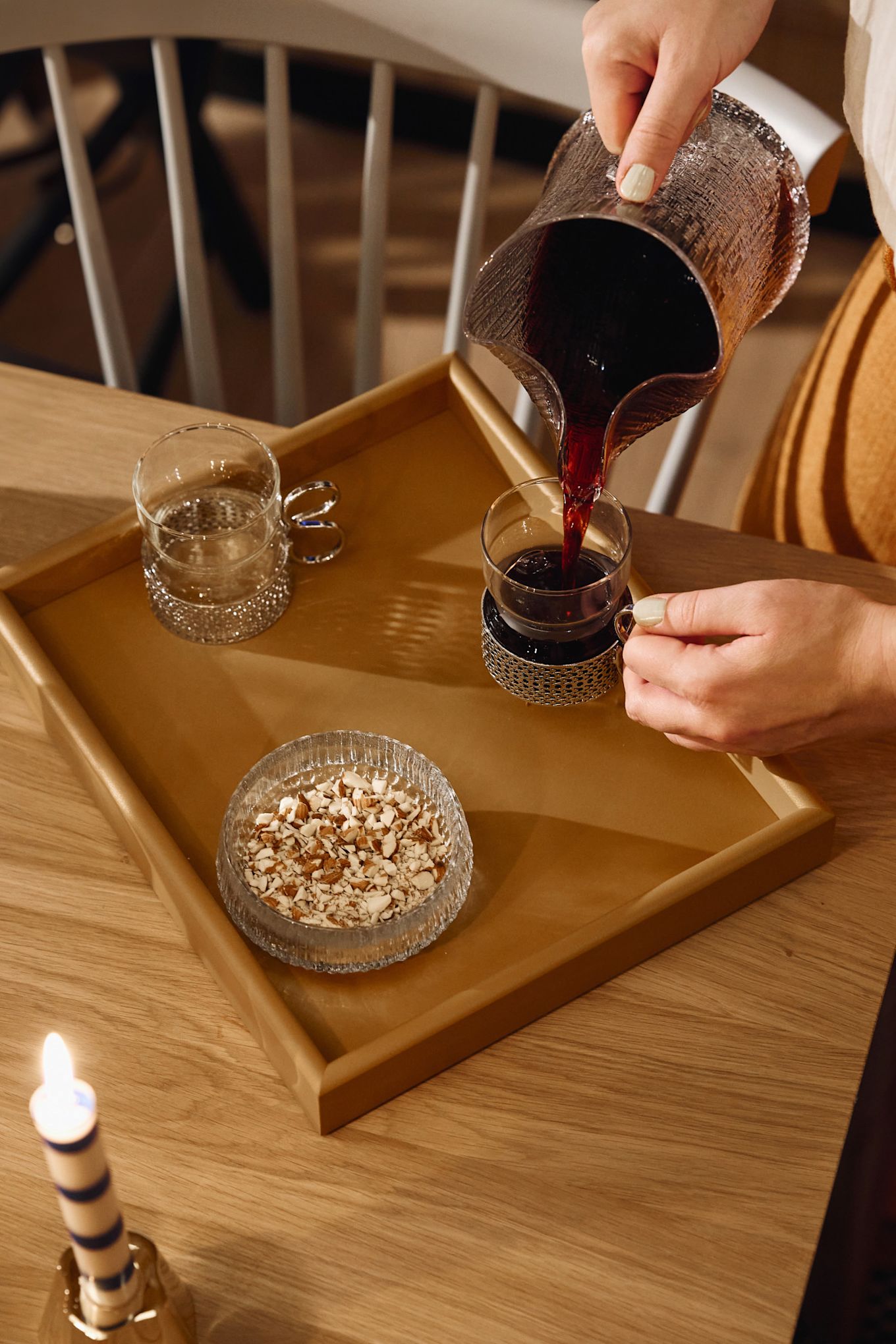 Mulled wine is poured from a glass jug into a glass glöggmug. 