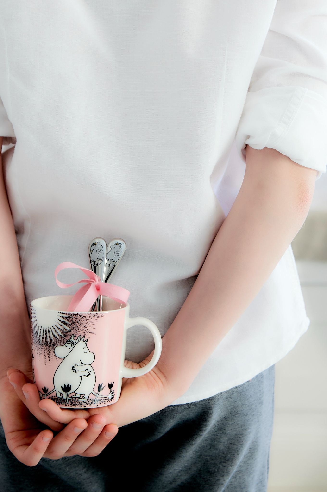 A boy hides the Moomin cup ‘Love’ by Moomin Arabia with the Moomin spoons ‘Love’ by Hackman behind his back.