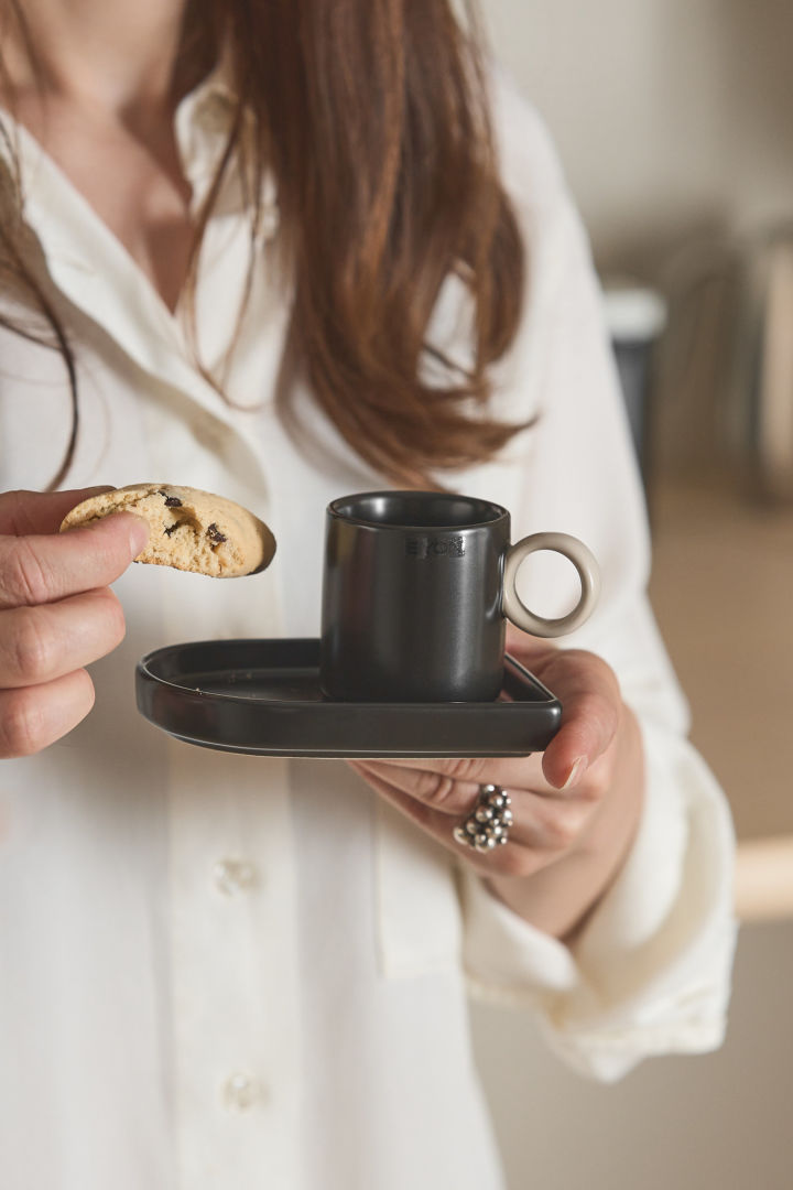 Here you can see a woman holding the Niki espresso cup from Byon in one hand and a biscotti in the other.