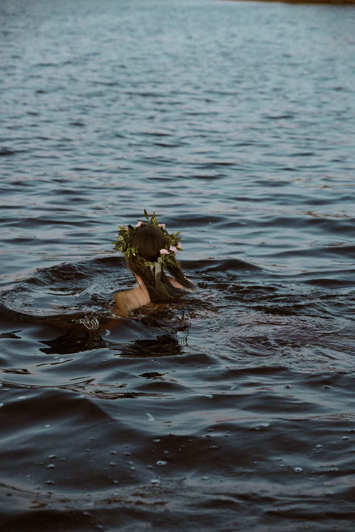 Be sure to add a cold dip to you summer bucket list. Here a woman swims in the sea with a midsummer crown.