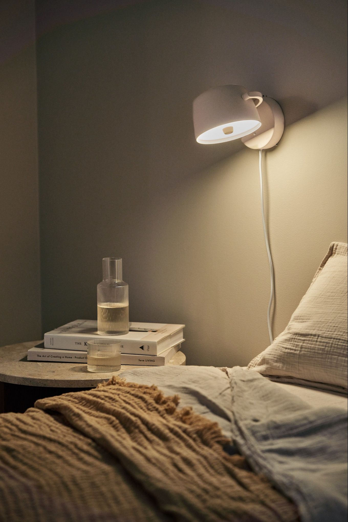 Refresh your home with modern wall lighting - here you see the Halo wall lamp from Scandi Living in beige on the wall above a bed. 