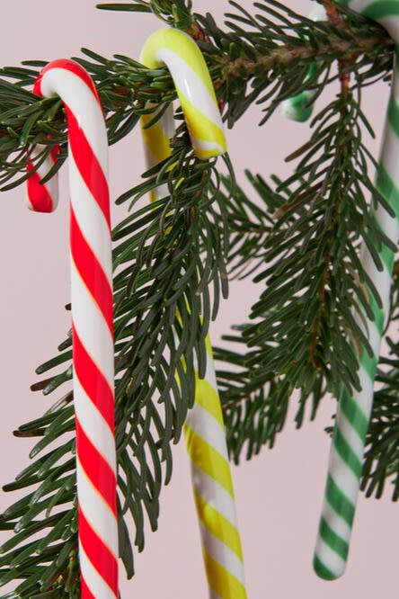 A hand places a large wrapped candy tree decoration into a Christmas tree a playful and colourful Christmas tree decoration idea. 