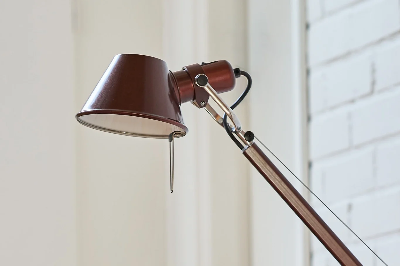 Close-up of a brown adjustable desk lamp with a conical shade and chrome accents.