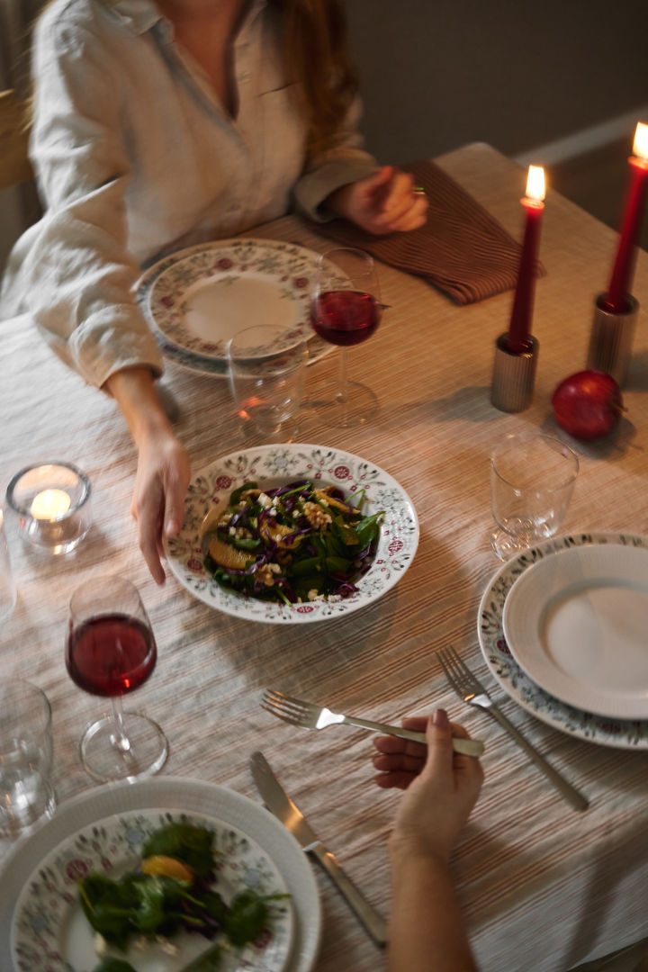 A hand passes a winter salad across the table as part of a Scandinavian Christmas table setting idea. 