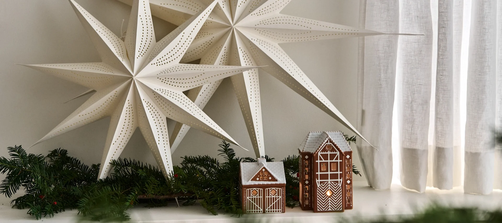 Modern and minimalist Christmas décor in a Scandinavian living room. Here you see two Scandinavian Christmas stars in a neutral coloured living room with a pair of gingerbread houses.