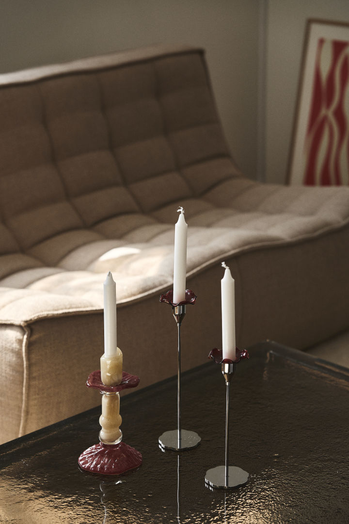 Lara candlestick from Byon, here on a coffee table with glass top, is made of coloured glass in beige and burgundy, the design is inspired by Roman columns.