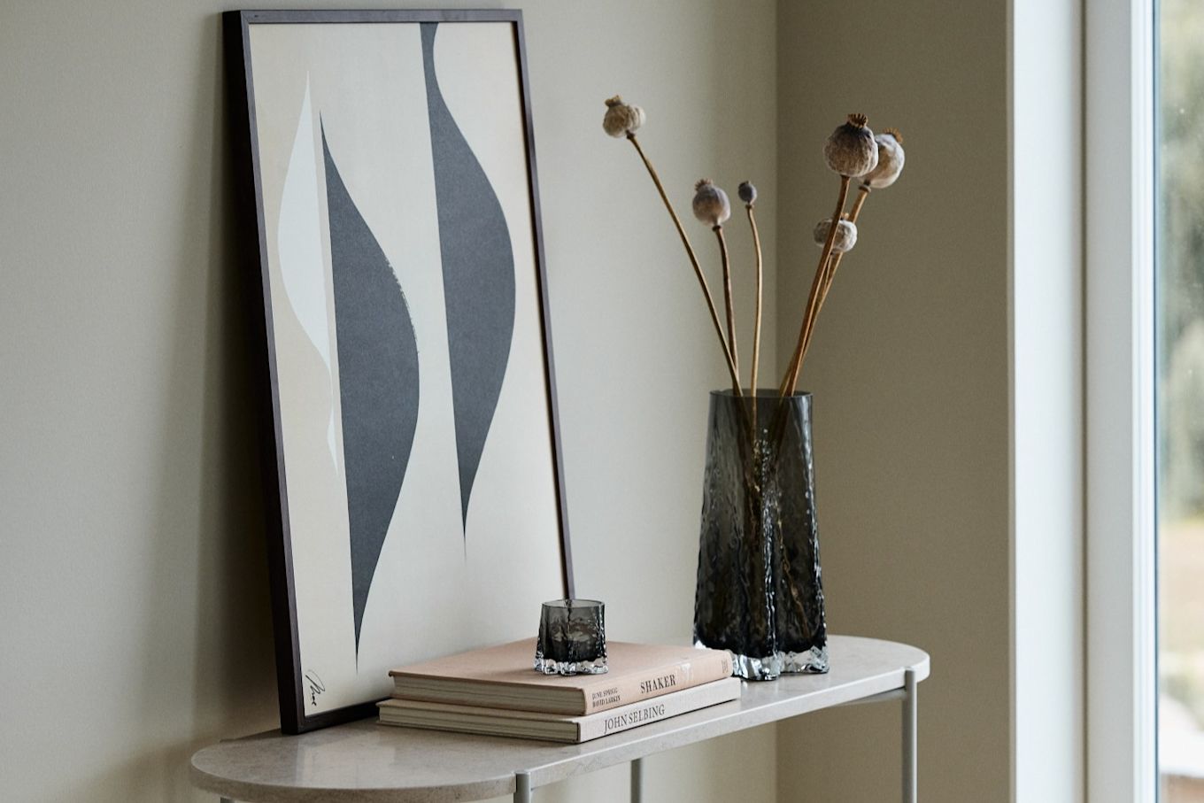 Here you see the Gry vase 30cm and the Gry candle lantern both in the colour Smoke from Cooee Design standing on a sideboard in front of a print.  