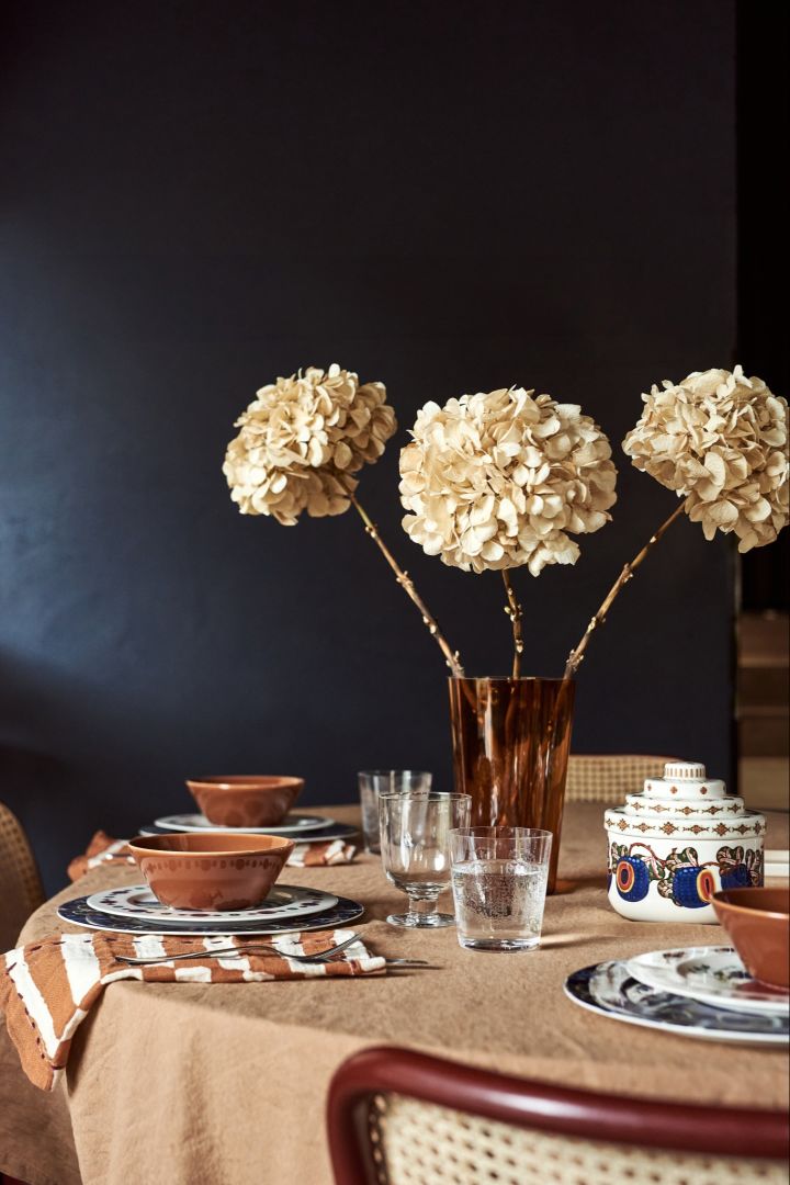 Here you see the Alvar Aalto vase in brown standing on a table with a rustic bohemian theme. 