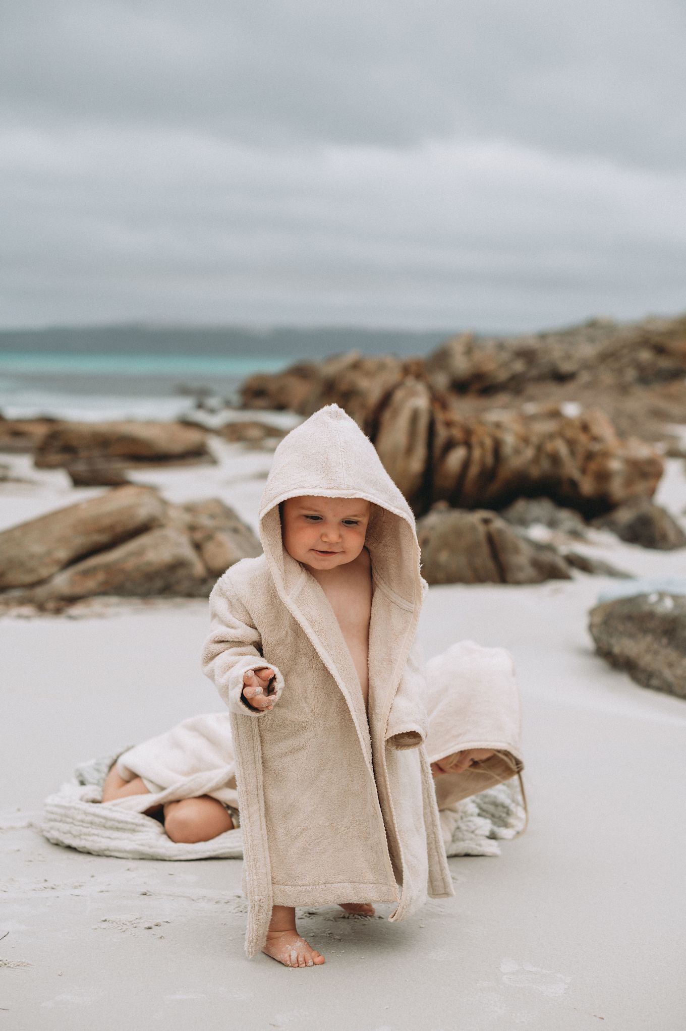 A baby lays on a towel with a hood in a matching baby grow from Garbo&Friends - perfect baby shower gift ideas. 