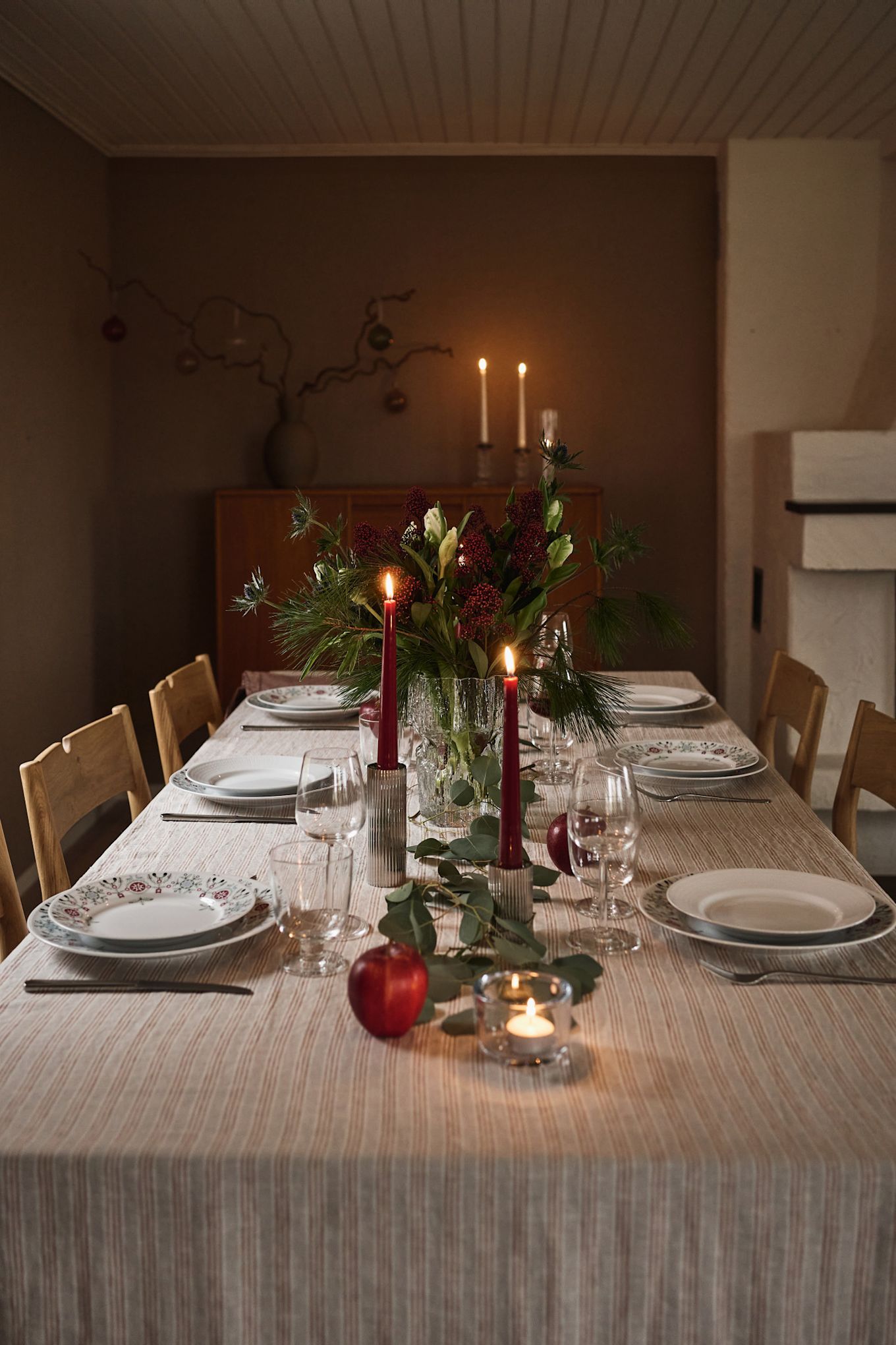 An atmospheric and simple Christmas table setting idea with red candles and printed Christmas tableware. 