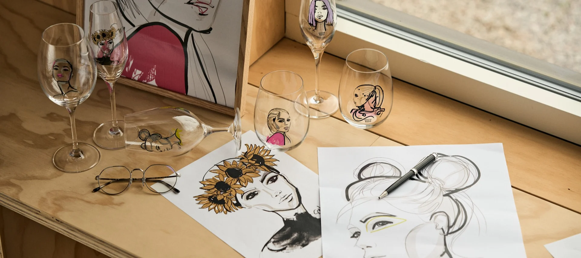 The All About You collection, designed by Sara Woodrow for Kosta Boda, the series of glasses collected in a window on a plywood bench.