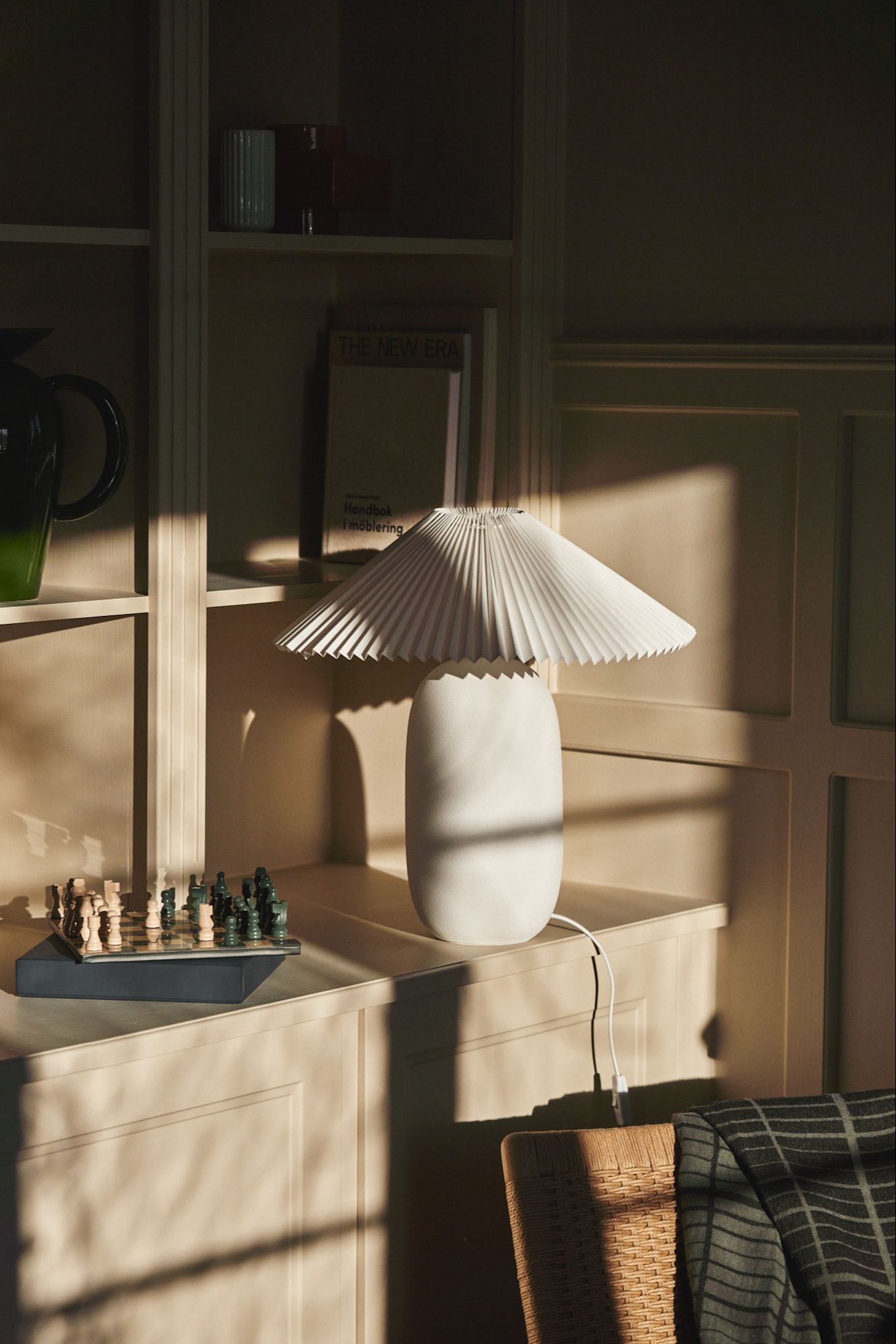 Refresh your home with these modern lighting ideas. Here you see the textured Boulder lamp from Scandi Living in a bookcase bathed in late afternoon light. 