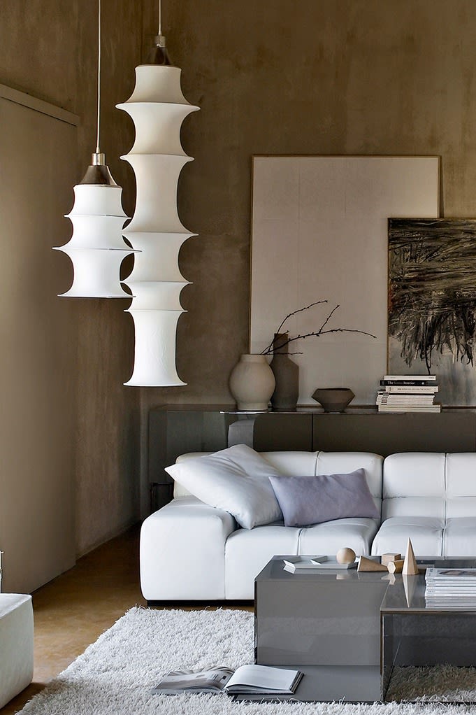 Two Falkland pendant lamps from Artemide hang in a living room in neutral colours. 