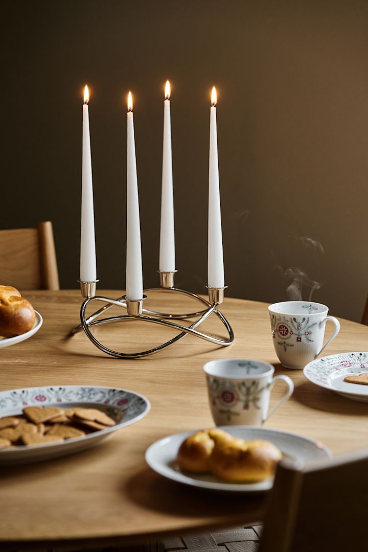 The Season advent candle stands on a Christmas table with ginger bread biscuits and saffron buns. 