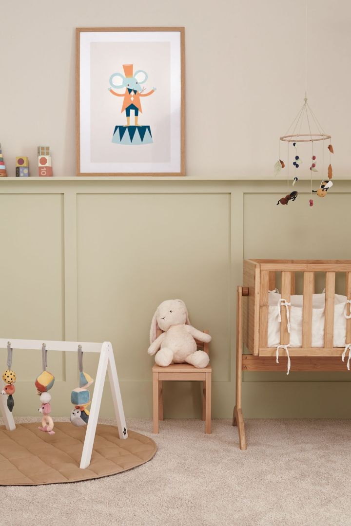 An image of a baby's nursery with a mobile hanging over a cot and a floor gym on the floor. Mobiles make perfect baby shower gift ideas. 