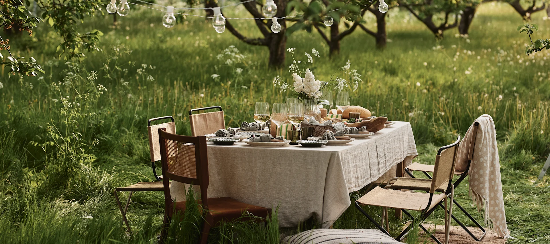 Discover our garden party inspiration - an elegant table setting in the garden with soft textiles, neutral table linens, hanging and portable lights.