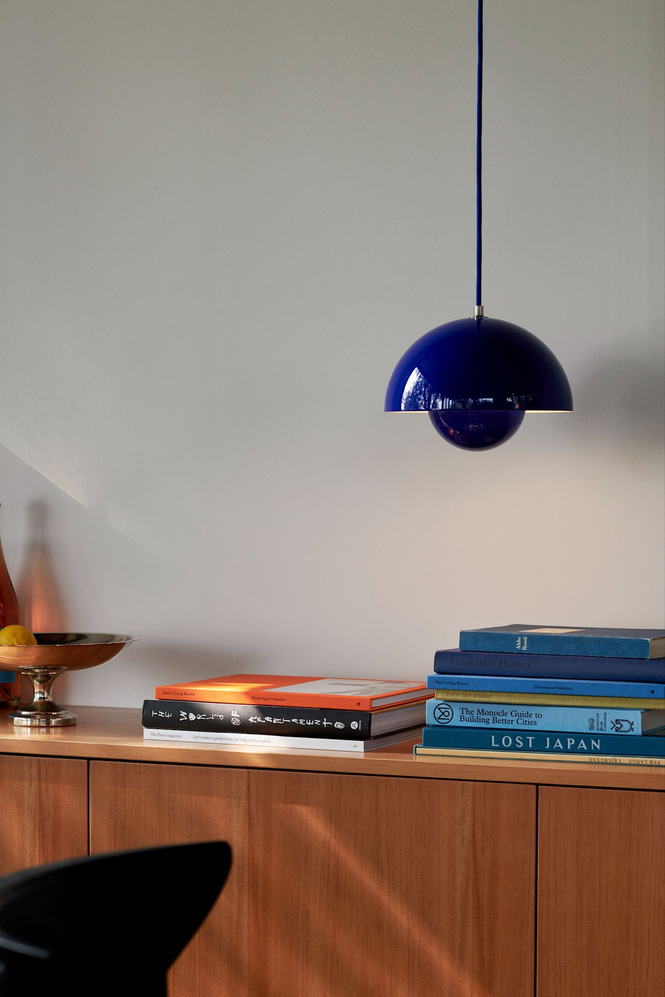 Image showing the classic Flowerpot VP10 ceiling light from &Tradition in the colour cobalt blue, here hanging over a teak sideboard.