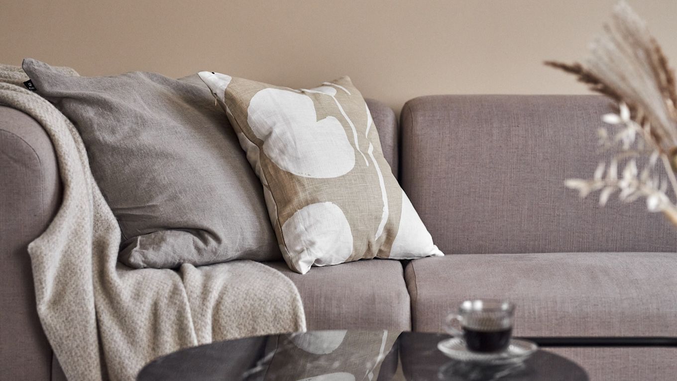 Cozy beige living room in classic scandinavian interior design with pillows and throws on a couch. 