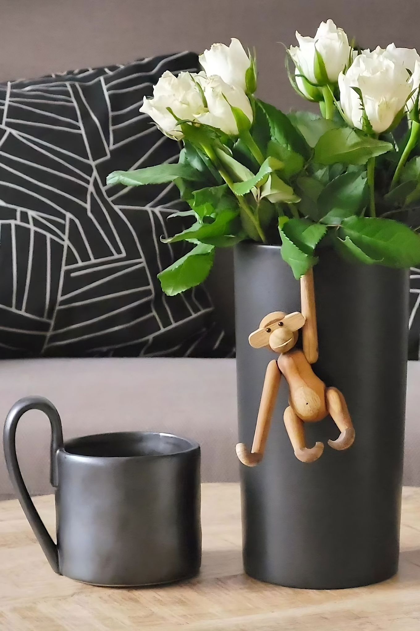 Give a cute monkey from Kay Bojesen as a Mother's Day gift, shown here hanging from a black vase with white tulips, next to the Flow mug from Ferm Living, in the home of @despina2024.