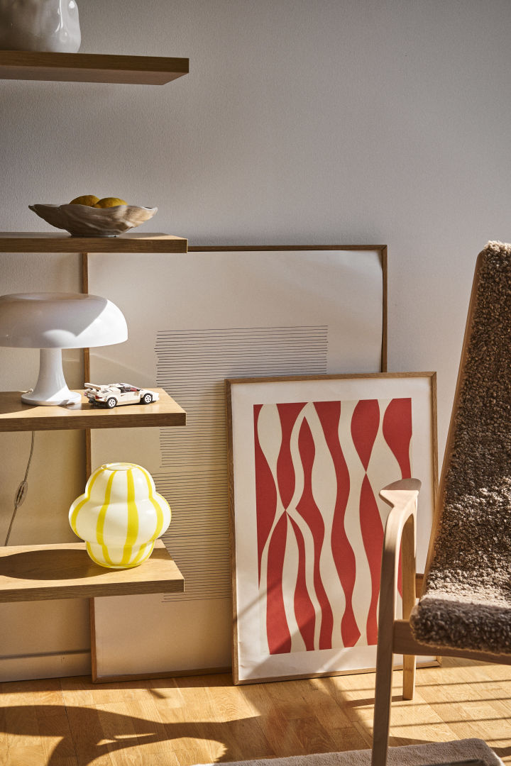 Curlie vase from Byon has a round, bulbous design in yellow and white striped glass. Here placed in an open bookcase together with Shell bowl, lamps and paintings.