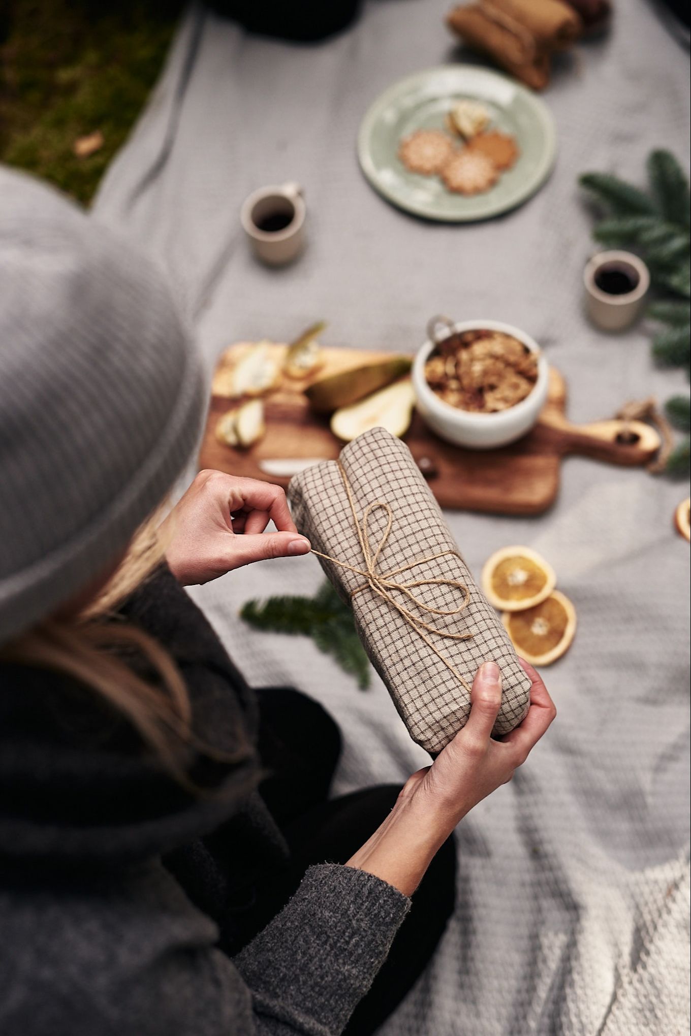 A Christmas present, wrapped in a tea towel with string, is carefully opened.