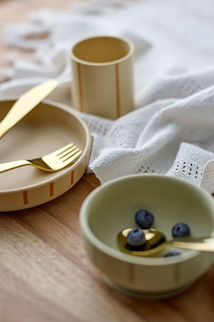 The Levi children's plates and bowls from Bloomingville on a wooden table. Cutlery and bowls make great baby shower gift ideas. 