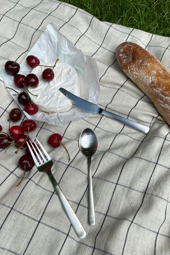 Here you see the Grand Prix cutlery from Kay Bojesen on a picnic blanket with bread and cheese. 