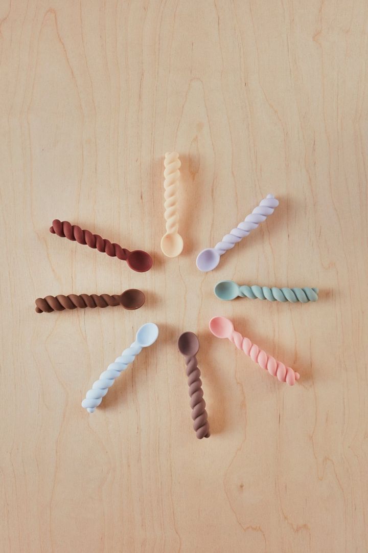 Baby spoons from OYOY with twisted handles are arranged in a circle. Cutlery makes an idea baby shower gift idea. 