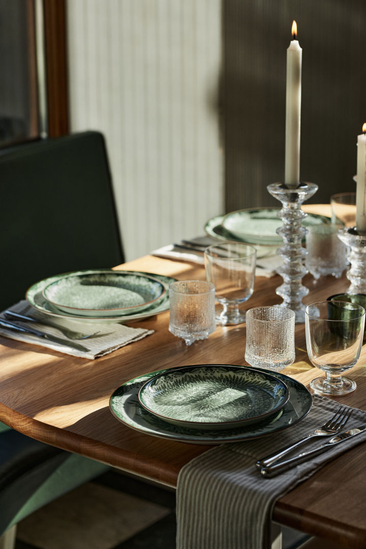 Here you see a table setting with the classic Ostindia tableware in green and a stripey linen napkin in a restaurant-style table setting at home. 