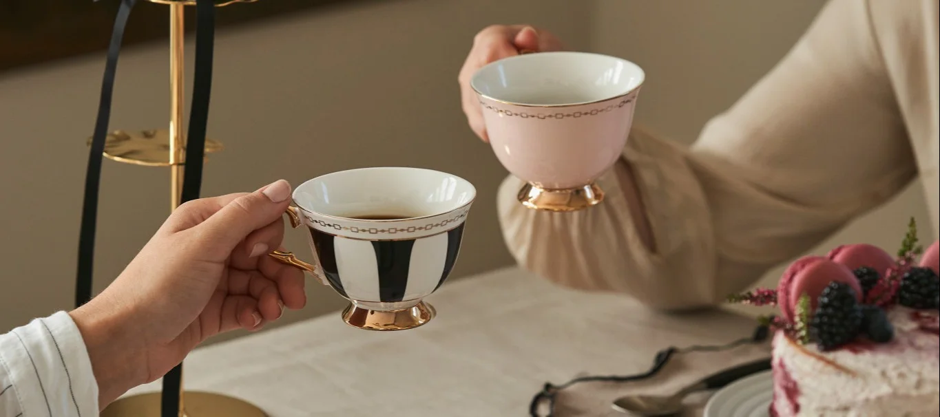 Celebrate Galentine's Day with a traditional afternoon tea with your girlfriends. Here you see two friends raising cups of tea in traditionally shaped tea cups from Hilke.