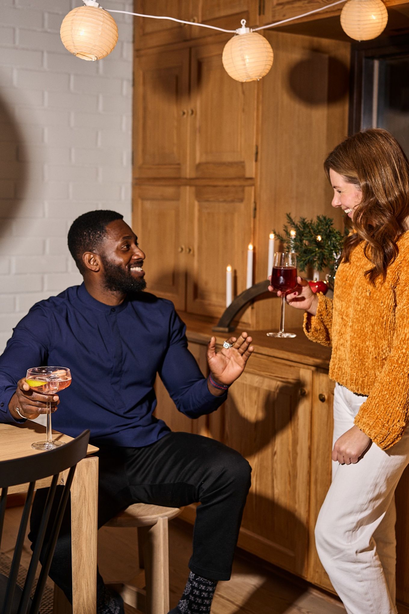 Friends laugh together with drinks during a traditional Nordic Christmas celebration. 