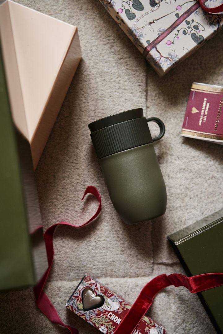 A colourful Marimekko mug held in the palm of a hand, a unique and cosy Christmas gift idea. 