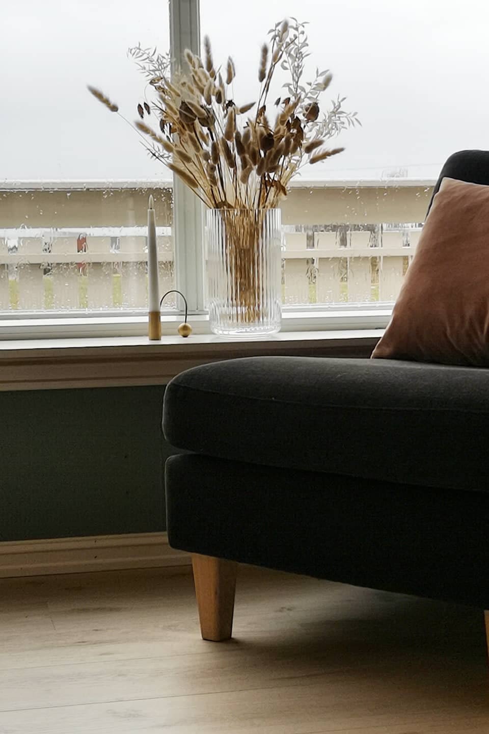 Flowers and plants are also great for decorating your windowsill. In @gisketun1957's home, you can see part of an armchair with a low windowsill behind it, decorated with a Lyngby glass vase from Lyngby Porcelæn with dried flowers and a Balance brass candle holder from ferm LIVING with an LED candle.