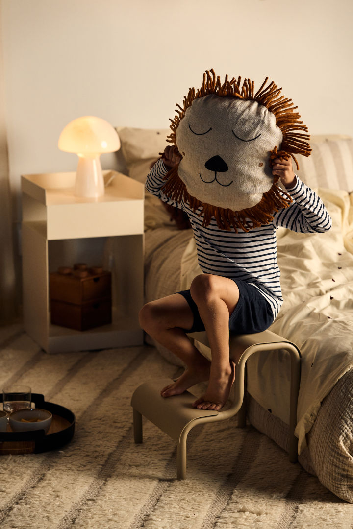 A child holds the lion pillow from ferm living in front of his face, pillows and details allow the child to bring personality in their room, a great idea for any children's room. 