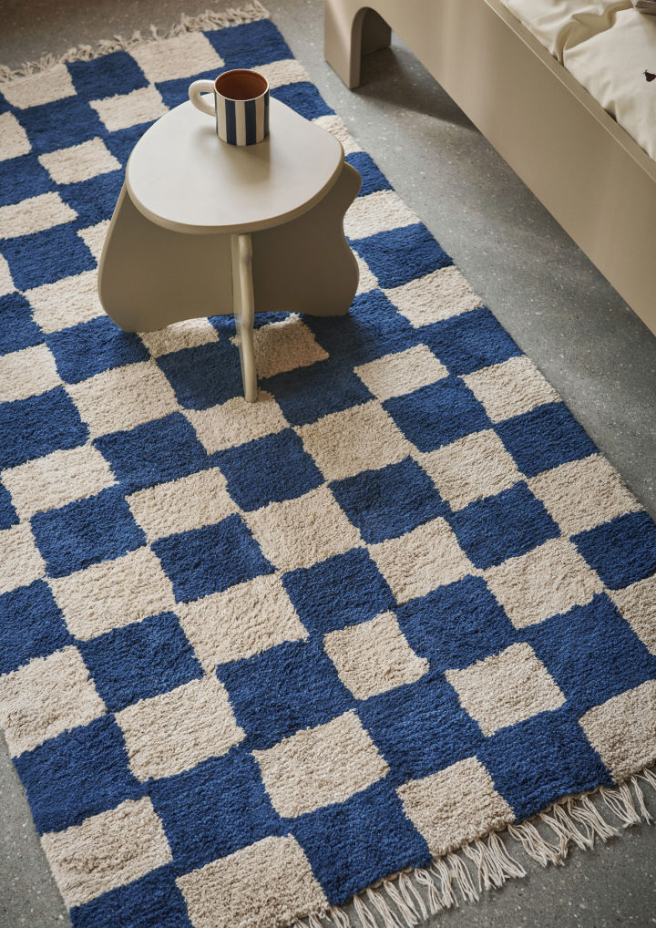 A side table stands on a blue and cream checked rug, the perfect idea for a children's room. 