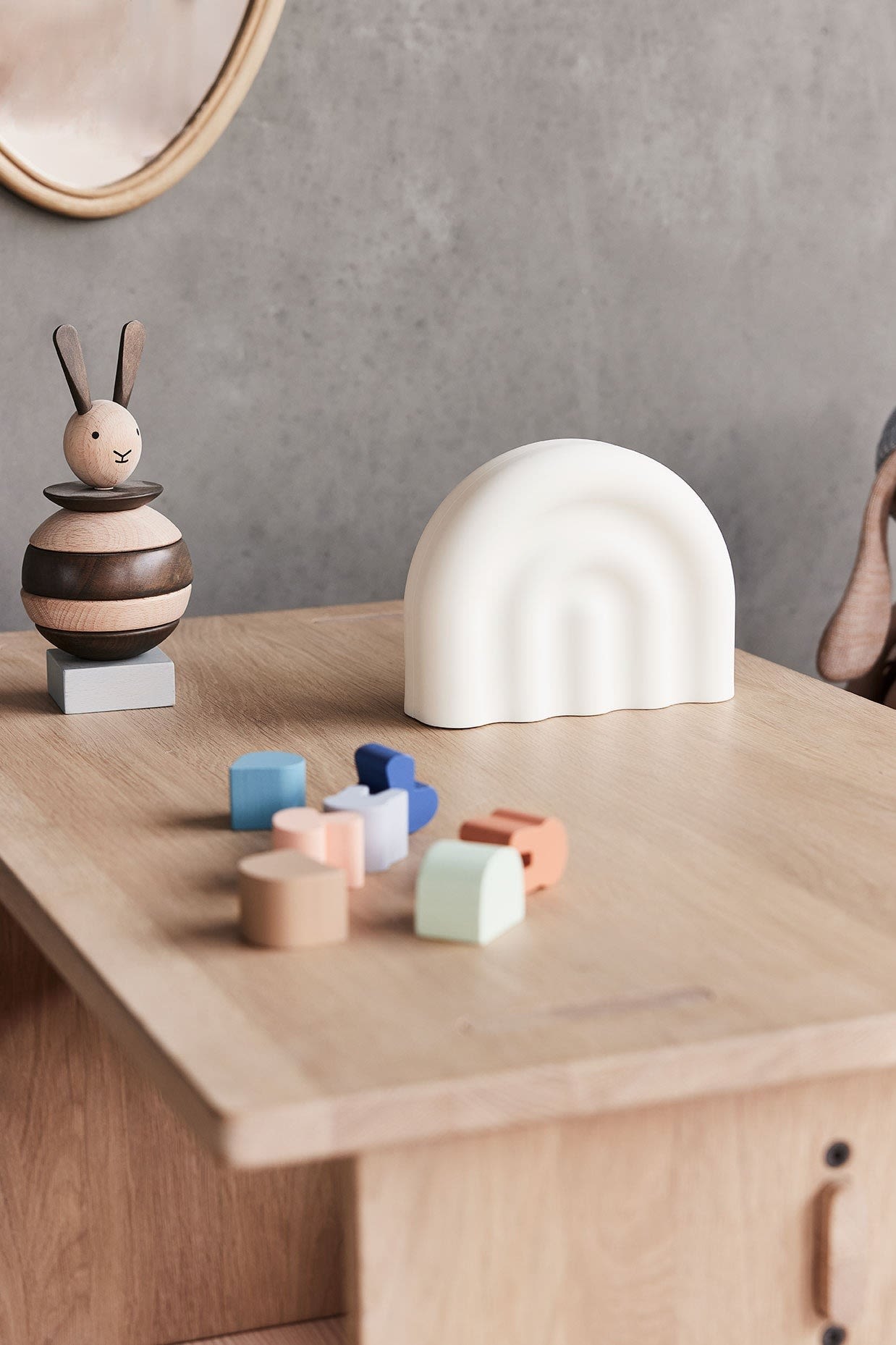 Here you see the rainbow night light from OYOY on a wooden table along with some wooden children's toys. Portable lamps are a practical baby shower gift ideas.