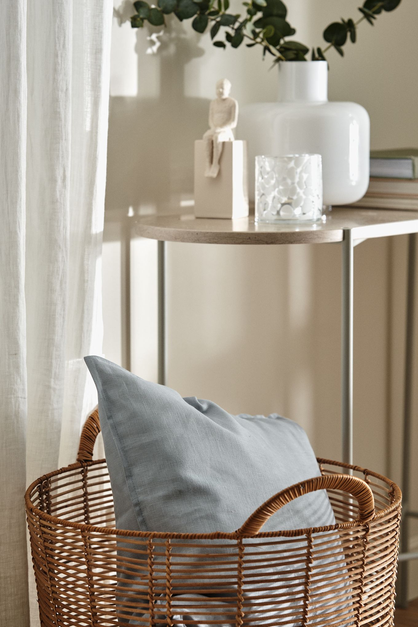 Sky blue linen cushion, lying in a basket in a beige living room.