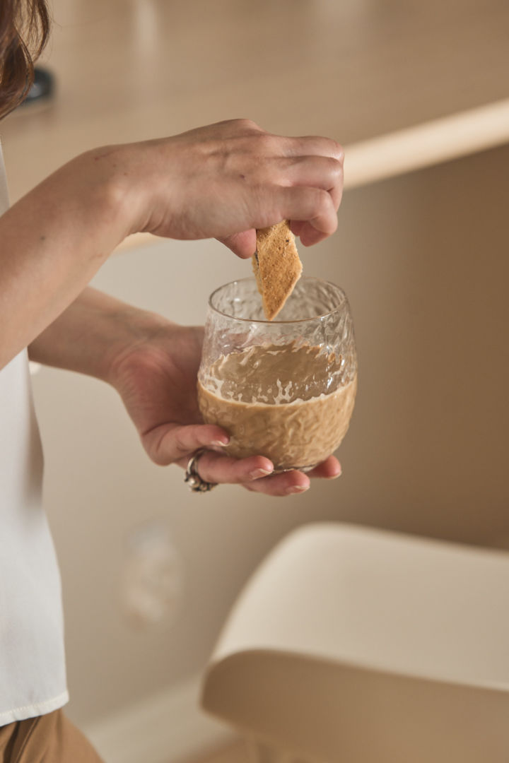 Here you can see a woman holding Byon's Swan jar of coffee with one hand and dipping a biscuit in it with the other.